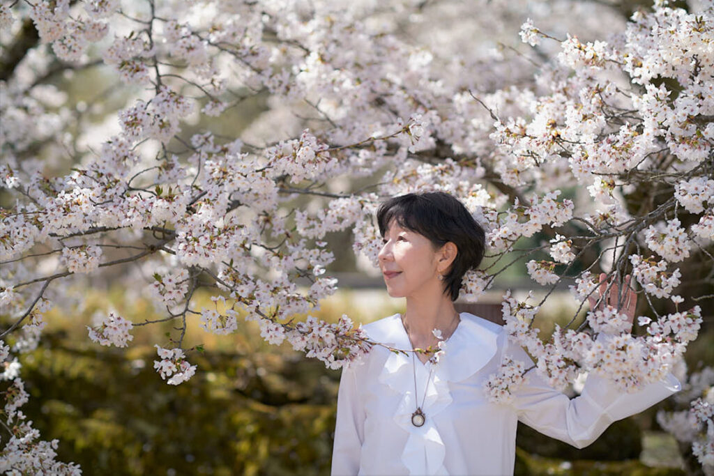 随筆家・石川真理子の私塾マリコアカデミィ「この花咲くや会オンライン講座」。女性としての品格と美しさを高める。満開の桜に包まれる石川真理子（撮影：魚住心）