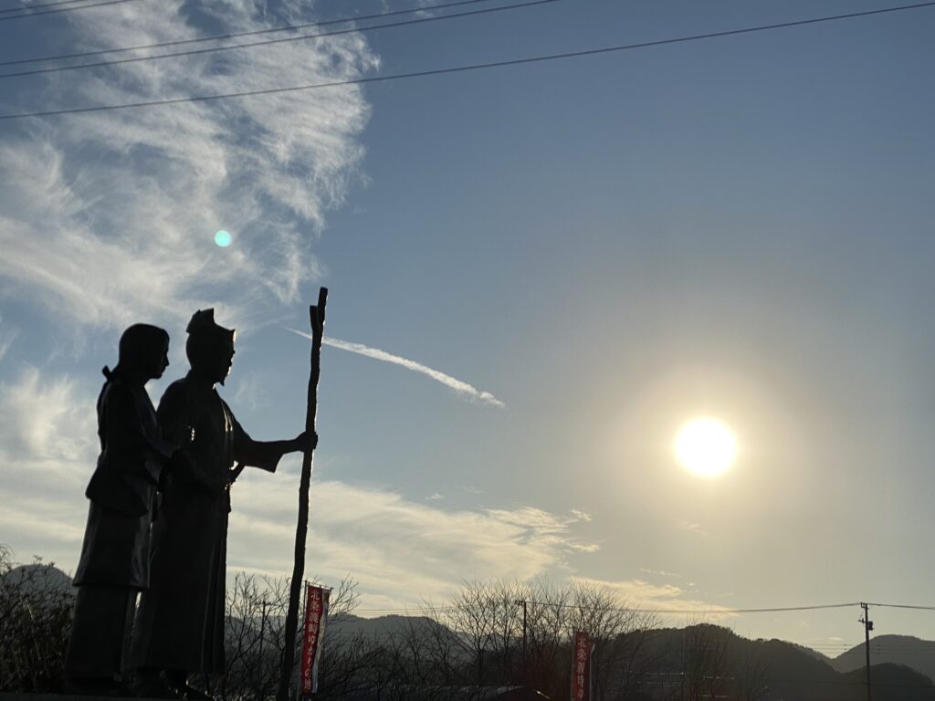 伊豆・韮山にある北条政子と源頼朝の夫婦像。逆境を共に乗り越え、武家政権の礎を築いた二人が、未来（歴史の夜明け）を見つめるシルエット。