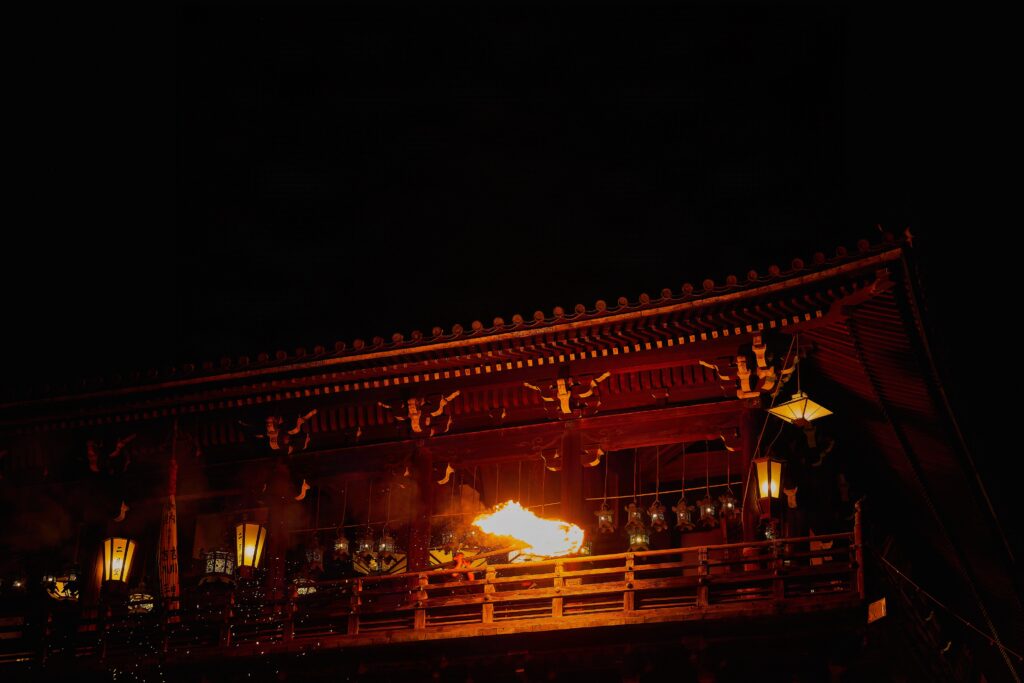 夜の闇に浮かび上がる東大寺二月堂の舞台と、静寂の中に灯る一筋の祈りの炎